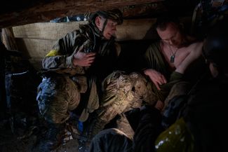 Бойцы «Эдельвейса» осматривают повреждения, полученные одним из них во время штурма российских позиций в лесу под Синьковкой