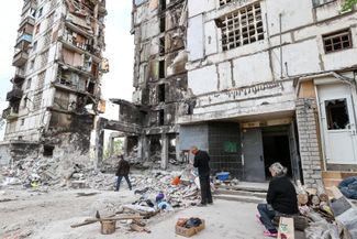 People next to a building destroyed by shelling in Mariupol. May 13, 2022