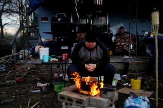 24-летний Кристофер Боулин готовит еду возле своего дома в Мэйфилде после торнадо