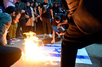 Сторонники «Хизбаллы» сжигают флаг Израиля в Бейруте. 7 октября 2023 года