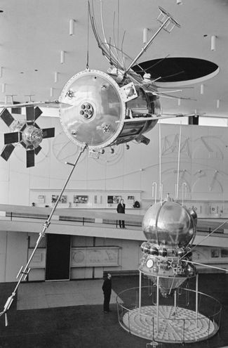 Автоматическая межпланетная станция «Венера-1» (сверху на первом плане) и космический корабль типа «Восток» (снизу) в зале ракетной техники Государственного музея истории космонавтики имени К. Э. Циолковского. Калуга, 6 октября 1967 года