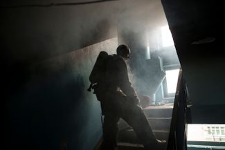 Пожарный тушит горящий жилой дом после обстрела Харькова российскими войсками