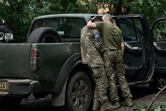 Украинский военный плачет на плече сослуживца после возвращения в Украину из Курской области