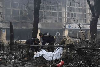 Police cover the bodies of people who died the previous day in an airstrike on the main Kyiv television broadcast tower