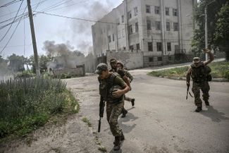Украинские военнослужащие бегут в укрытие во время обстрела в Лисичанске