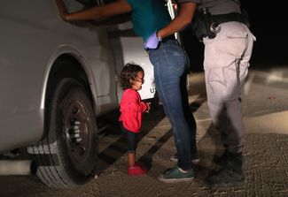 Американские полицейские обыскивают мигрантов, которые хотят попросить убежища в США, 12 июня 2018 года.