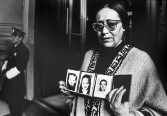 Женщина показывает фотографии своей дочери и внучки которых похитили в период правления военной хунты. 24 августа 1985 года