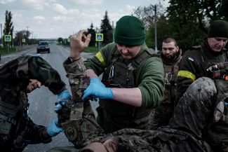 Отряд ВСУ помогает раненому солдату перед его транспортировкой в больницу. Лисичанск