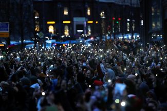 Протестующие зажигают фонарики на мобильных телефонах