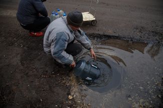 Жители города набирают воду на улице