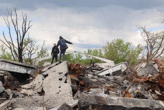 Украинские подростки на развалинах обстрелянного здания в селе Малая Рогань