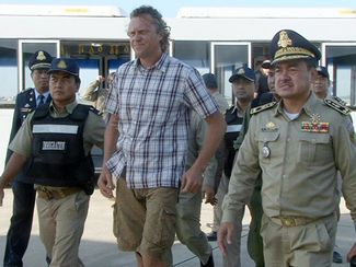 Сергей Полонский в сопровождении камбоджийской полиции в аэропорту Пномпеня. 17 мая 2015 года