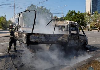 Пожарный тушит автомобиль, поврежденный в результате удара по центру Донецка