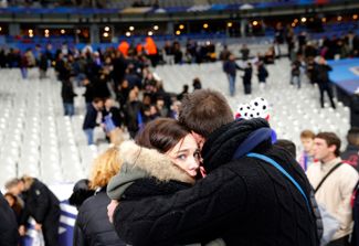 Зрители, пришедшие на стадион «Стад-де-Франс», обнимают друг друга после сообщения о взрыве возле него. 13 ноября 2015 года