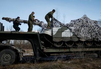 Украинские военные снимают маскировочную сеть с танка, который привезли с передовой для ремонта в северную часть Украины (куда именно — не уточняется)