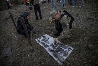 Украинские саперы собирают осколки от российского снаряда, попавшего по городу