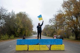 Житель Херсона с флагом Украины рядом с блокпостом на въезде в город. До отступления российских войск блокпост контролировался ВС РФ. 13 ноября 2022 года