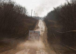 Mobil Dinas Darurat Negara meninggalkan desa Kalinovka.  Kolom asap dari api terlihat di cakrawala