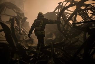 Украинский пожарный на территории разрушенного авиаударом склада продуктов на окраине Киева