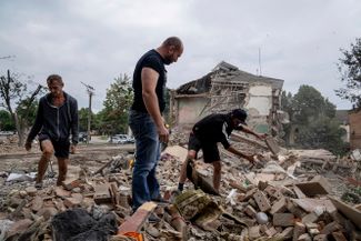 Жители Чугуева ищут документы своего раненого друга в развалинах разрушенного жилого дома