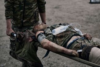 Боец ВСУ несет раненого товарища в полевой госпиталь на передовой в Бахмуте