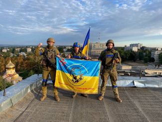 Украинские военные с флагом на крыше здания в Купянске Харьковской области