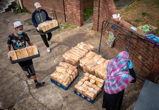 Сотрудники благотворительной организации из Йоханнесбурга готовят еду для раздачи во время карантина, 19 мая 2020 года