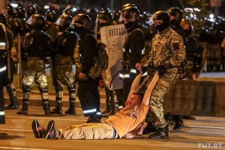 Силовик тащит мужчину по земле во время протестной акции после закрытия избирательных участков. 9 августа 2020 года