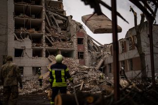 Спасатели разбирают завалы в частично разрушенном в результате обстрела здании в Чернигове