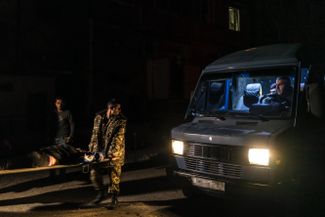 Раненого военного несут в машину после атаки беспилотника по военному штабу. 2 октября 2020 года