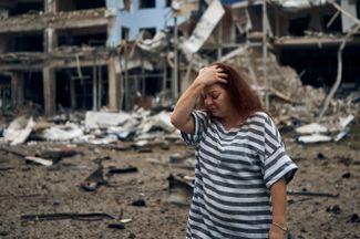 Женщина на фоне разрушенного здания в Николаеве
