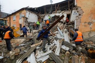 Рабочие разбирают завалы на месте жилого дома в Горловке, пострадавшего во время обстрелов