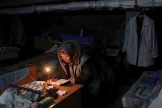 Женщина молится, укрываясь от обстрела в школьном подвале. Харьков, Салтовка