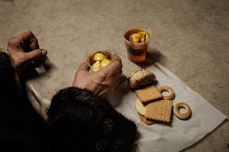 Пожилая жительница Бахмута пьет чай с печеньем в центре гуманитарной помощи