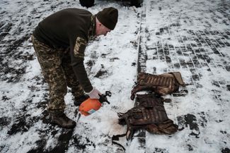 Украинский фельдшер очищает от крови бронежилет одного из раненых бойцов ВСУ