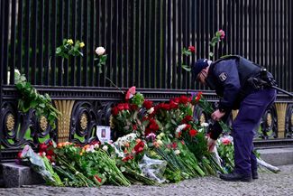Берлин. Цветы рядом с посольством России кладет офицер немецкой полиции