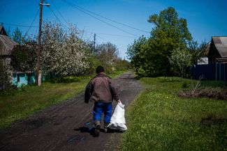 44-летний житель Северска Александр Ващенко несет мешок с гуманитарной помощью своим соседям