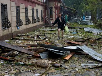 Житель Николаева идет мимо жилого дома, поврежденного во время российской атаки