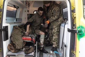 Военные врачи ВСУ помогают раненому украинскому солдату выйти из машины скорой помощи