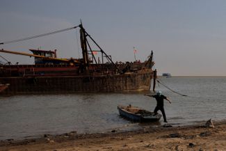 Мужчина выходит на берег крупнейшего пресноводного озера Китая Поянху, которое обмелело из-за засухи, 24 августа 2022 года