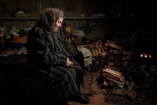 71-летняя Любовь Степанова греется у печки в подвале многоквартирного дома, где вместе с ней живет еще около 20 человек