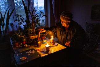 Пожилая жительница Херсона зажигает свечи у себя дома