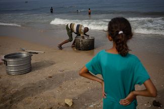В условиях дефицита пресной воды жители сектора Газа используют для некоторых бытовых нужд морскую воду. На фото — морской водой моют большие чаны для приготовления пищи. Пляж в городе Дейр-эль-Балах. 2 ноября 2023 года