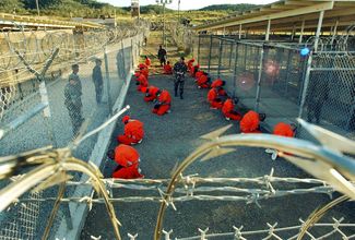 Заключенные ожидают распределения в камеры в тюрьме на военной базе в Гуантанамо, 18 января 2002 года
