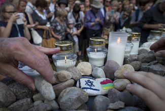 Участники марша памяти жертв холокоста кладут камни к мемориалу убитых евреев Молетая