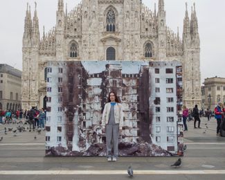 39-летняя редактор Наталья в Милане перед фотографией Максима Дондюка, запечатлевшего разбомбленный многоквартирный дом в одном из населенных пунктов Луганской области
