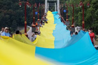 Активисты держат 430-метровый флаг Украины на пешеходном мосту через Днепр. Акция «Украина едина» символически объединяет оба берега Днепра и демонстрирует связь с регионами страны, которые находятся под российской оккупацией