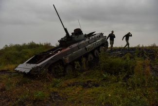 Украинские военнослужащие возле сгоревшей российской БМП-2 в Харьковской области