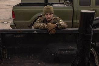 Украинский военный на фоне поставленных ВСУ пикапов с пулеметами