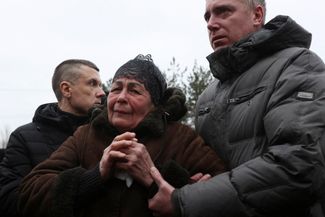 Жительница Днепра во время поминальной службы у дома, куда 14 января попала ракета